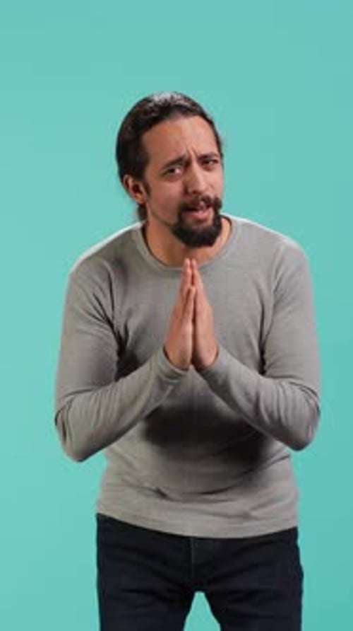 Man Pleading with Hands Clasped in Studio
