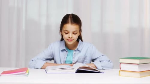 Smiling Girl Sitting Reading Open Book at Table