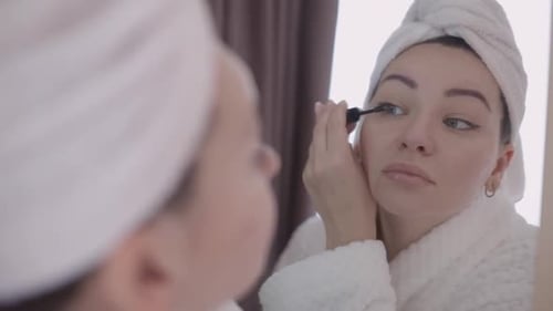 Woman Applying Mascara in Mirror Close Up