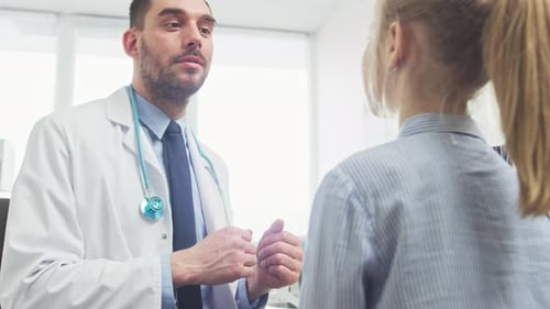Low Angle Shot of Friendly Doctor Explaining How Medicine Works to a Cute Little Girl and Her Mothe