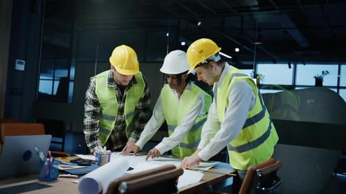 Multiracial Team of Architects and Engineers Discussing Blueprints in an Office During a Project