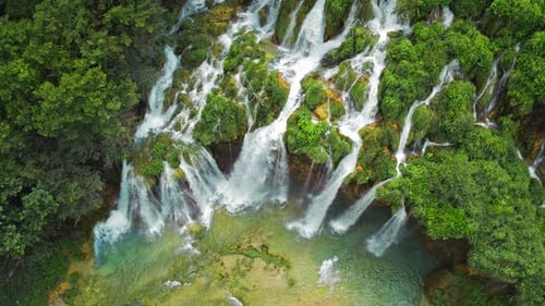 Waterfalls in summer rainforest and mountain landscape with clear water streams. Cascades flow among