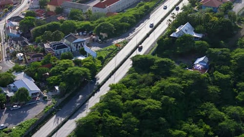 Drohne dringen über glitzernden, hellen Asphalt ein, als mittags Sonnenlicht auf ihn trifft, während Autos fahren
