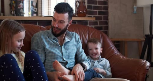 Happy Young Smiling Caucasian Father Playing with Little Son and Daughter at Home Family Fun Time