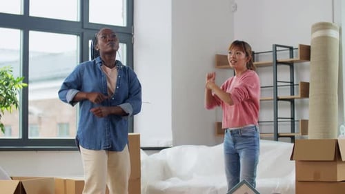 Moving, People And Real Estate Concept - Women With Boxes Dancing At New Home