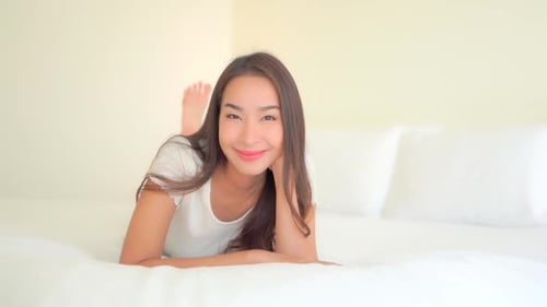 Smiling Brunette Lying on a White Bed