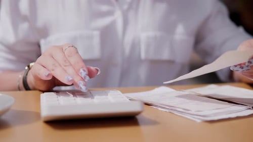Calculating Business Expenses at a Cafe in the Afternoon Sun With Detailed Paperwork
