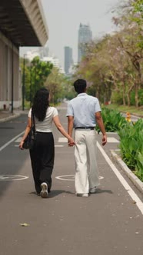 Loving Couple Walking Hand in Hand in a City Park