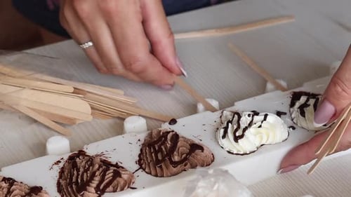 Une femme met des bâtonnets en bois dans de la crème glacée dans un moule en silicone. Fait de la crème glacée maison. Gros plan.