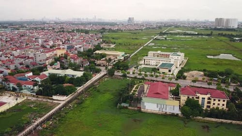 Aerial Over a Suburban Area in Asia with Houses Buildings and Green Field