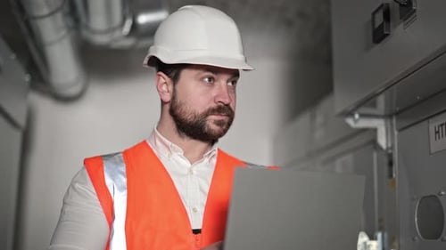 Engineer Working on Laptop in Industrial Setting