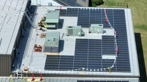 Large solar panel array on industrial factory building in USA. Rooftop green energy theme in America