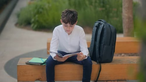 Boy Reading and Doing Homework Outside in Peaceful School Courtyard