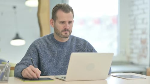 Adult Working with Laptop and Stylus in Office