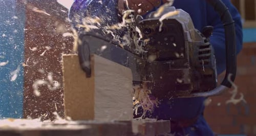 Close-up of chainsaw slicing wood plank, explosion of wood particles in super slow motion, fps
