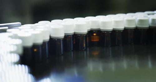 Close up of production of medicines in glassware bottles on automatic lines in a pharmaceutical fa