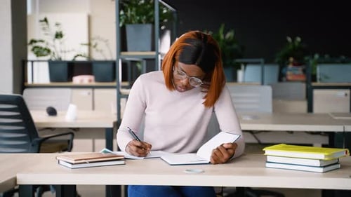 Konzentrierte junge Frau, die in einer modernen Bibliothek studiert