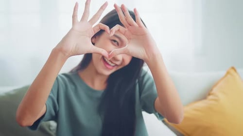 Smiling Woman Makes Heart with Hands Indoors