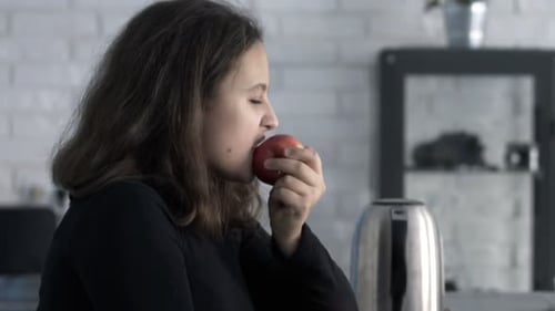 Teen Girl Using Laptop While Eating Red Apple