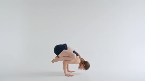 Woman Practicing Yoga Headstand and Arm Balance in White Studio