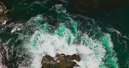 Agua aguamarina aplastando la roca escarpada que se asoma desde el océano.