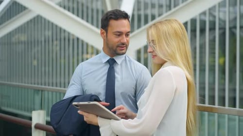 Happy Two Business People Discuss Project Details Looking at Tablet Computer In Office Building Venu