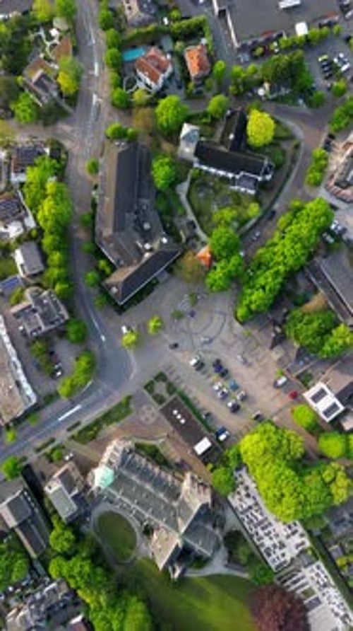 Aerial view of a town block with a central plaza multi story buildings church and tree lined roads.