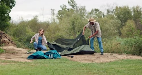 Couple Pitches Tent Together in Green Outdoors