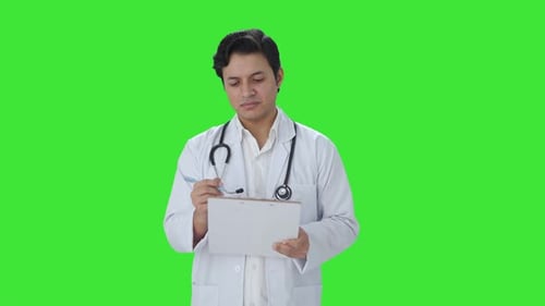 Confused Indian doctor writing patient brief Green screen