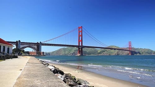 The Iconic Landmark of the Golden Gate Bridge in Bright Red Against a Blue Sky Along the Promenade a