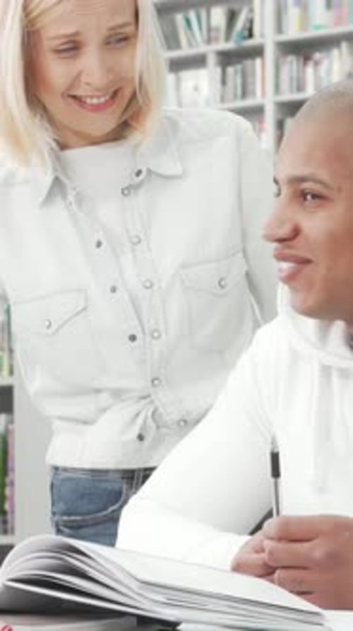 Charming College Couple Engaged in Lively Discussion While Studying at the Library