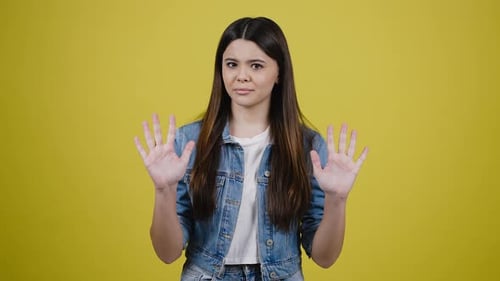 Cute Teenage Girl Gesturing with Thumbs Down Expressing Disagreement and Denial Yellow Background