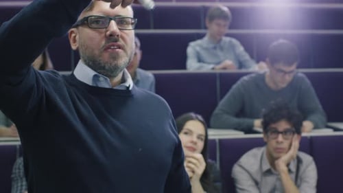 College professor is teaching a class of multi-ethnic students while pointing the desk with a marke