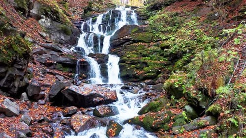 Narrow Stream Falling Down Mountain Slope in Autumn Forest
