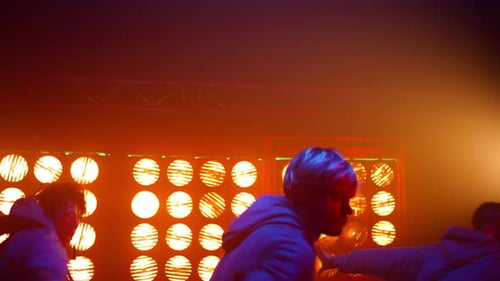 Energetic breakdance team moving synchronously in neon lights on night club stage