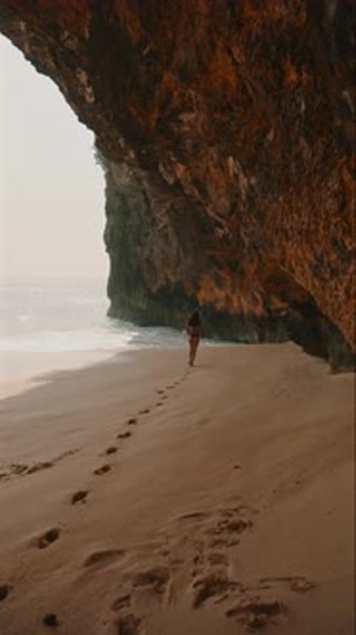 Woman Walking Along the Sandy Beach Under a Rocky Cliff on Nusa Penida Island