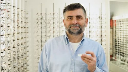 Hombre mayor que elige lentes de contacto en una tienda óptica moderna