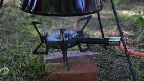 Pot Cooking Over Gas Stove Outdoors on Grass