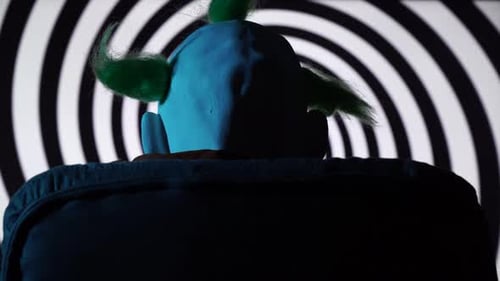 Back View of Psychopath Clown Sitting on Chair with Spinning Hypnosis Spiral