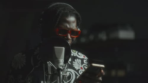 Black Musician Reading Lyrics on Phone and Singing in Recording Studio