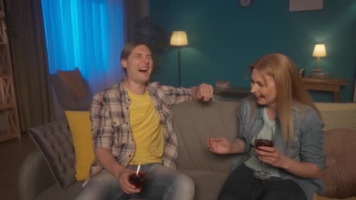A Couple is Sitting on the Sofa in the Evening Talking and Drinking Red Wine A Woman Shares the