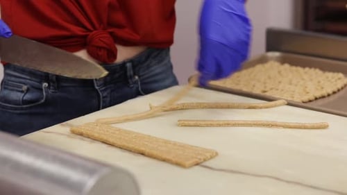 Bakery Worker Slicing Dough for Breadsticks