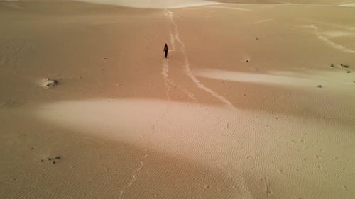 Aerial view of vast sand dunes with a woman walking, Spain.