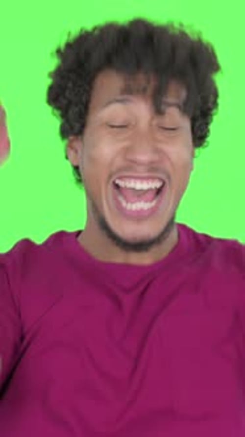 Erfolgreicher afrikanischer Mann feiert auf grünem Hintergrund, vertikales Video
