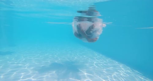 Underwater Shot: Unknown Male Jumping in a Swimming Pool and Sitting at the Bottom.