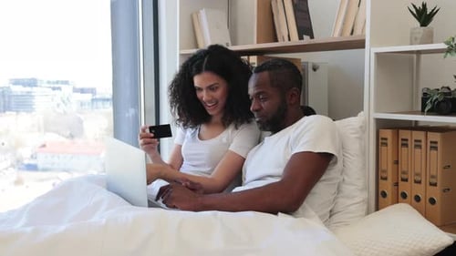 Couple Using Laptop with Credit Card in Bed