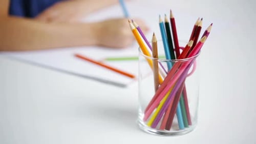 Child Drawing with Colored Pencils at Table