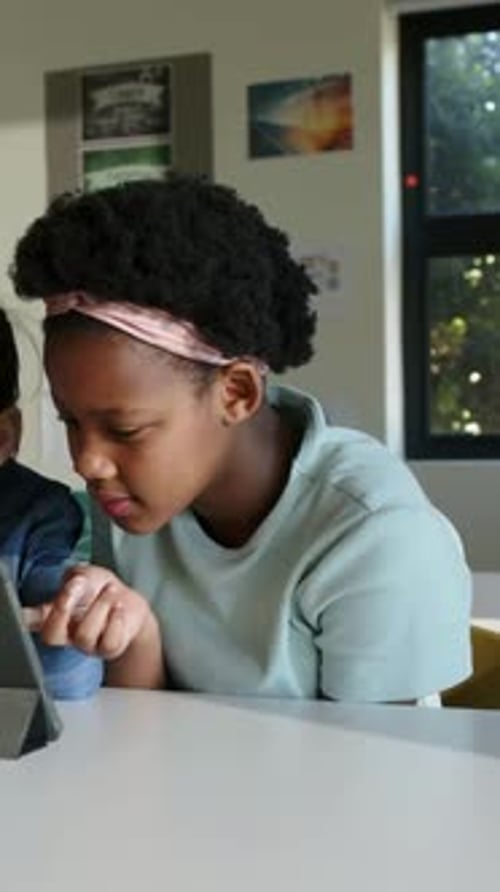 Student tapping tablet and initiating animated education charts, turning to classmate collaborating