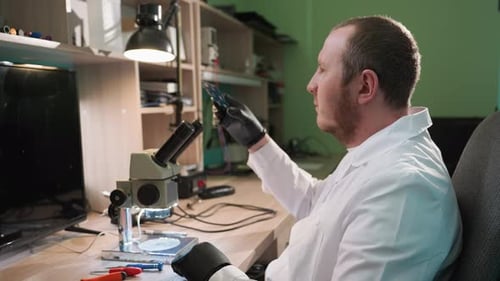 Techniker inspiziert Leiterplatte unter dem Mikroskop im Labor für organisierte Elektronik
