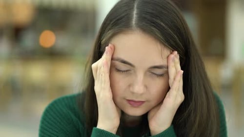 Portrait Unhappy Young Woman Sits and Holds Her Head with Her Hands